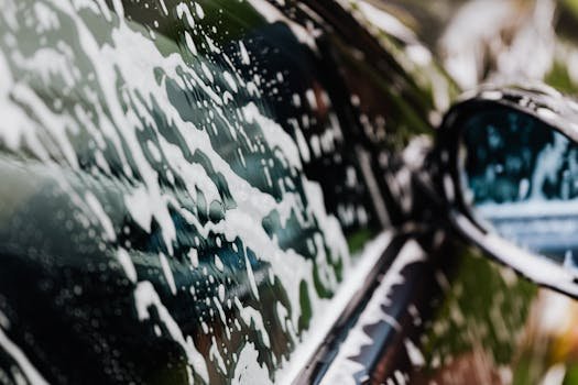 Detailed view of car covered in soapy foam during a wash, highlighting cleanliness.